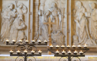 Lighted prayer candles in front of a carved altar screen at Great Yarmouth Minster.